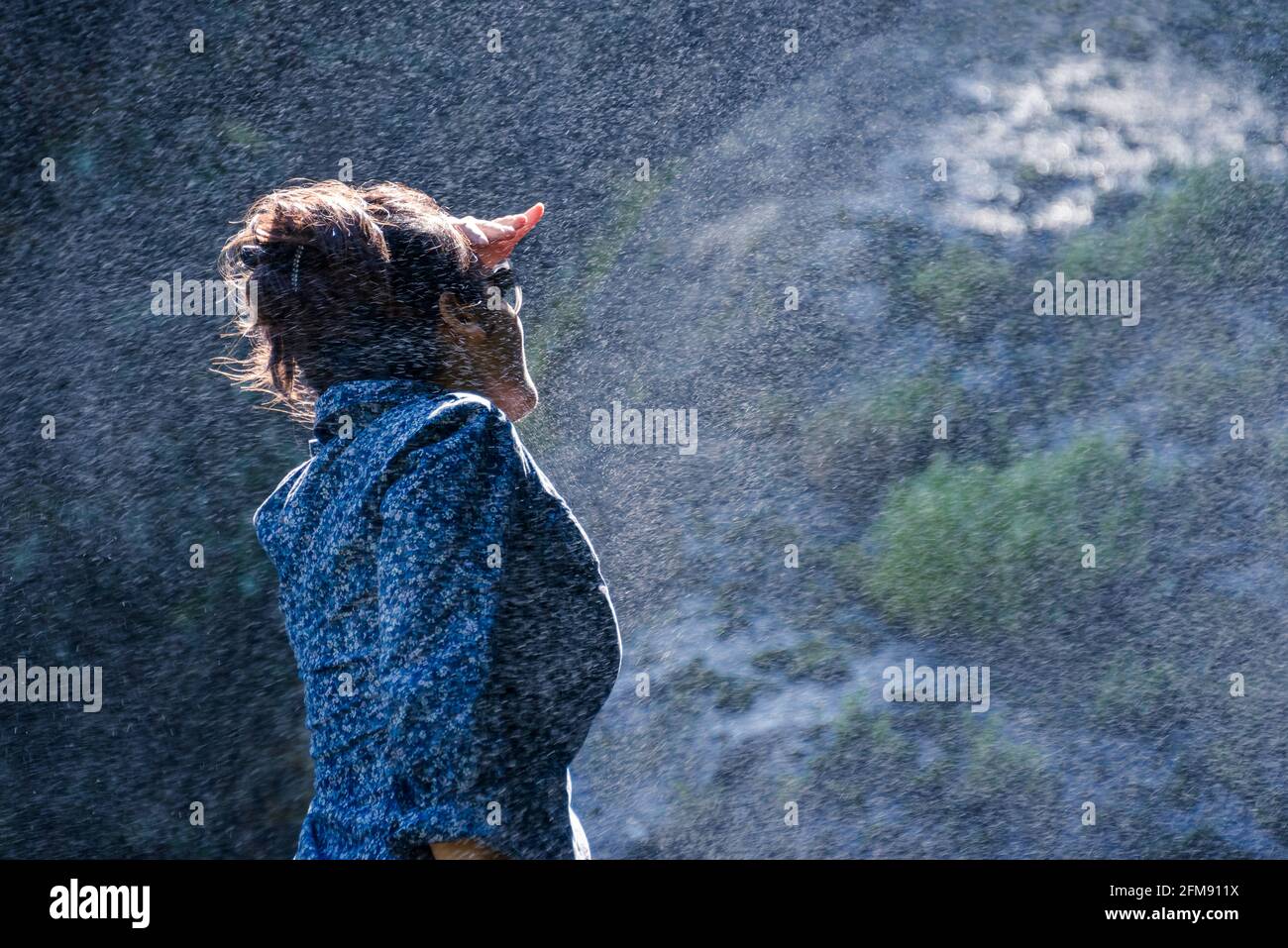 Junge nepalesische Frau, die im Wasserstrahl von einem steht Wasserfall Stockfoto