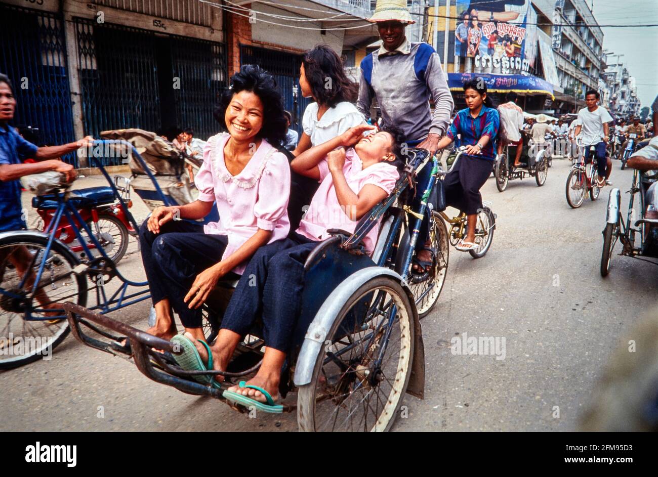 Lachende Frauen werden in einer Rikscha durch eine Einkaufsstraße in Phnom Penh getrieben. 27.06.1991 - Christoph Keller Stockfoto