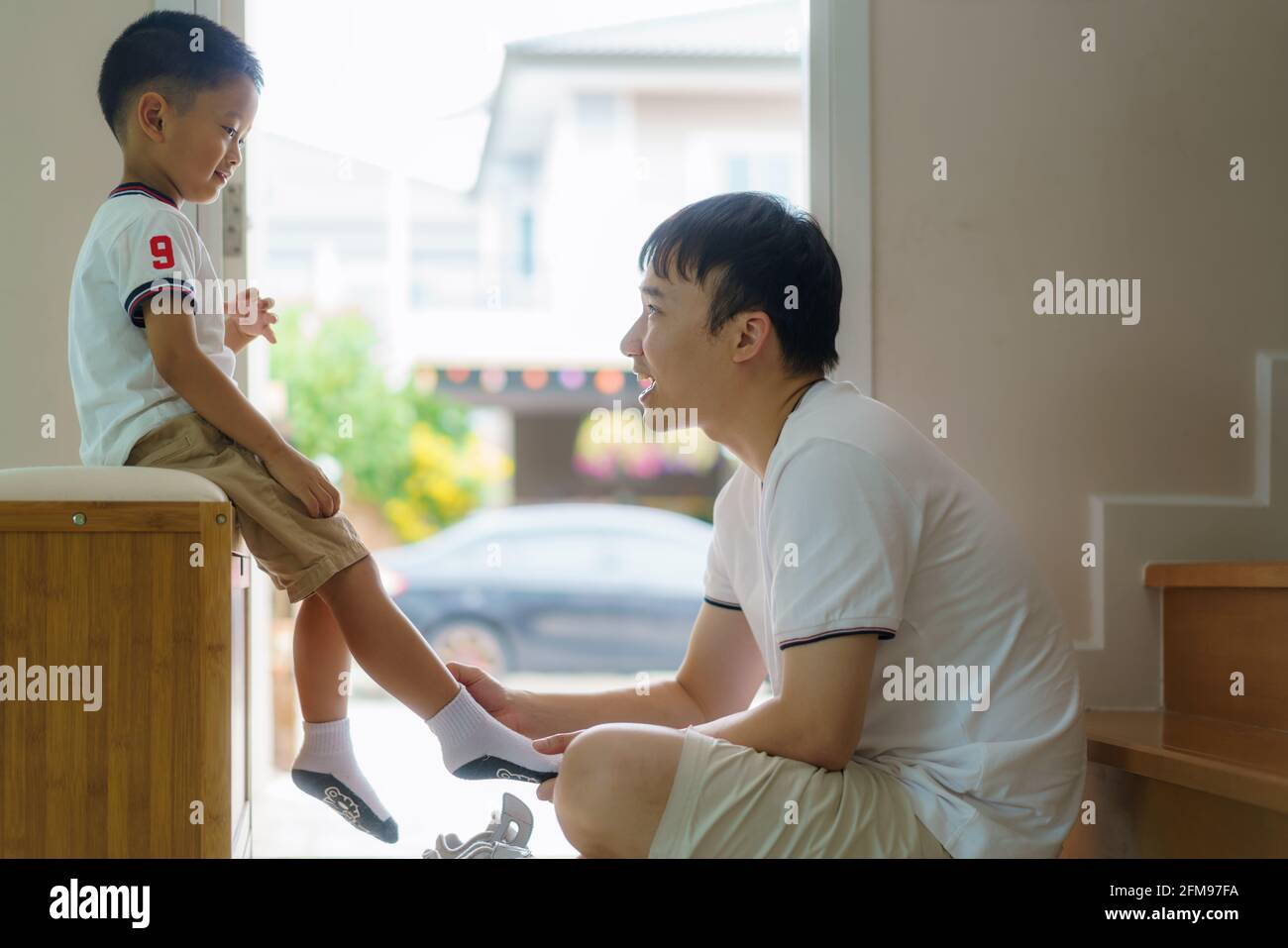 Der asiatische Vater trägt Socken für seinen Sohn, Väter interagieren den ganzen Tag über mit ihren Kindern. Stockfoto