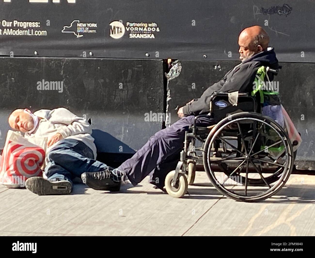 Obdachlose Männer streuen auf einem Bürgersteig, schlafen in der Morgensonne in der Nähe der 7th Avenue durch einen neuen Eingang zur Penn Station in Manhattan, New York City. Stockfoto