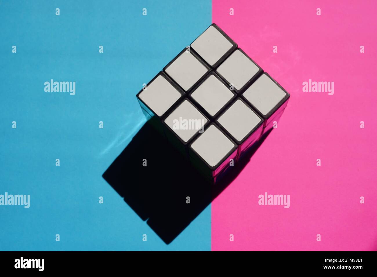 Rubik's würfelweiße Seite auf einem pinkblauen Tisch mit schwarzem Schatten. Stockfoto