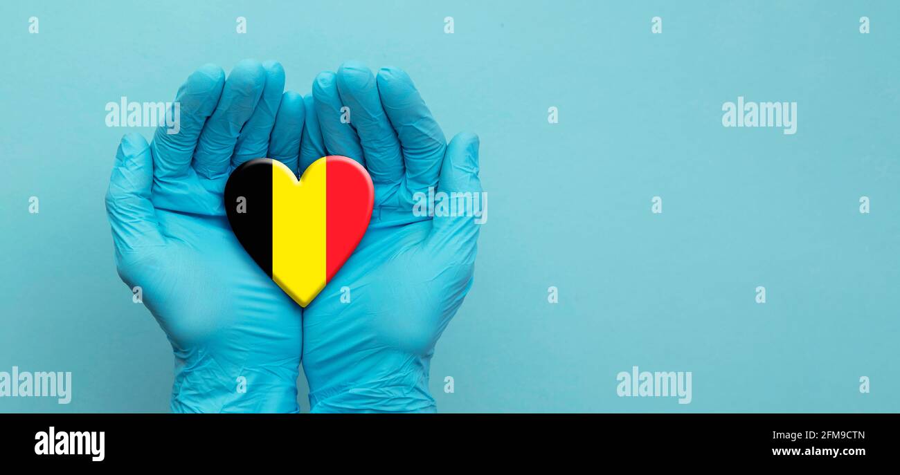 Ärzte Hände tragen OP-Handschuhe halten Belgien Flagge Herz Stockfoto