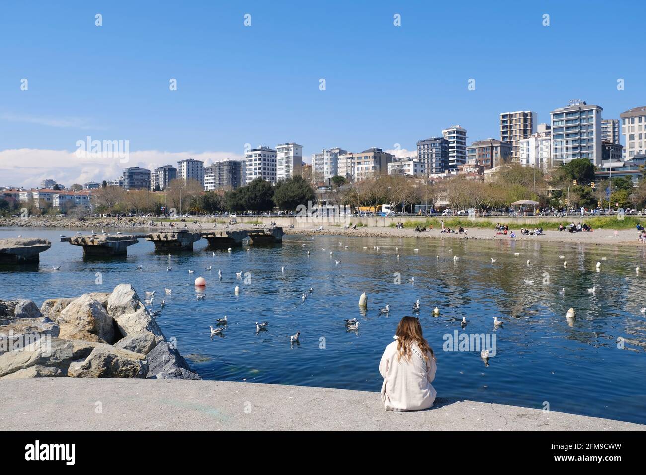 Istanbul, Türkei - 21. April 2021 : EINE junge Frau sitzt allein auf einem Betonsteg und beobachtet den Suadiye Beach in Kadikoy Istanbul. Viele pe Stockfoto