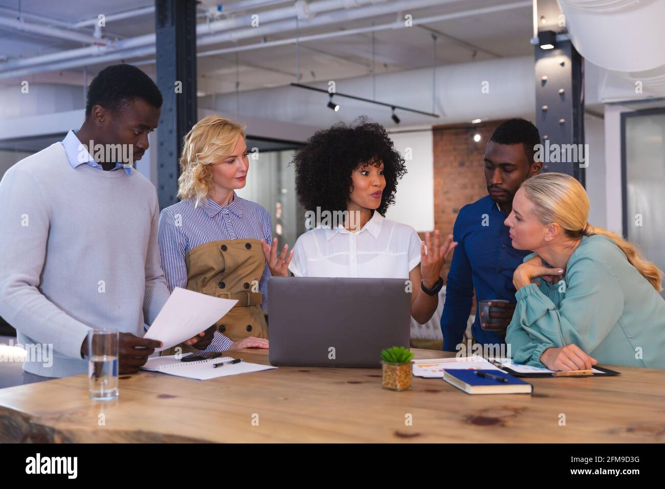 Ein Team aus verschiedenen Bürokollegen, die über einen Laptop miteinander diskutieren Im modernen Büro Stockfoto