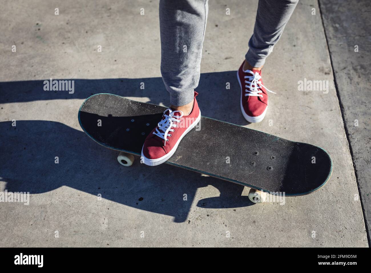 Niedriger Abschnitt der kaukasischen Frau, die auf dem Skateboard in der steht So Stockfoto