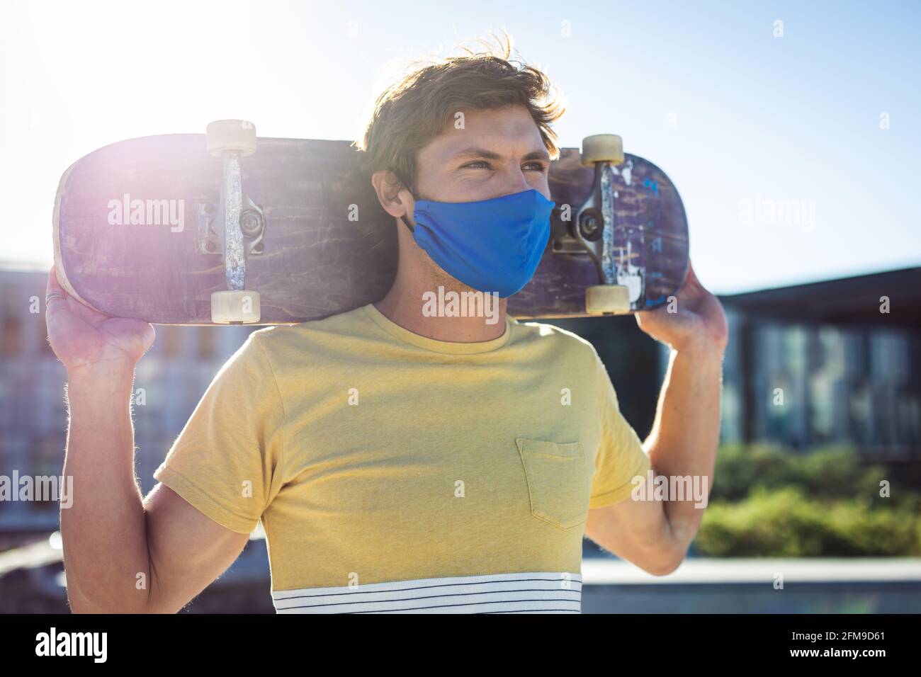 Kaukasischer Mann mit Gesichtsmaske und Skateboard Stockfoto