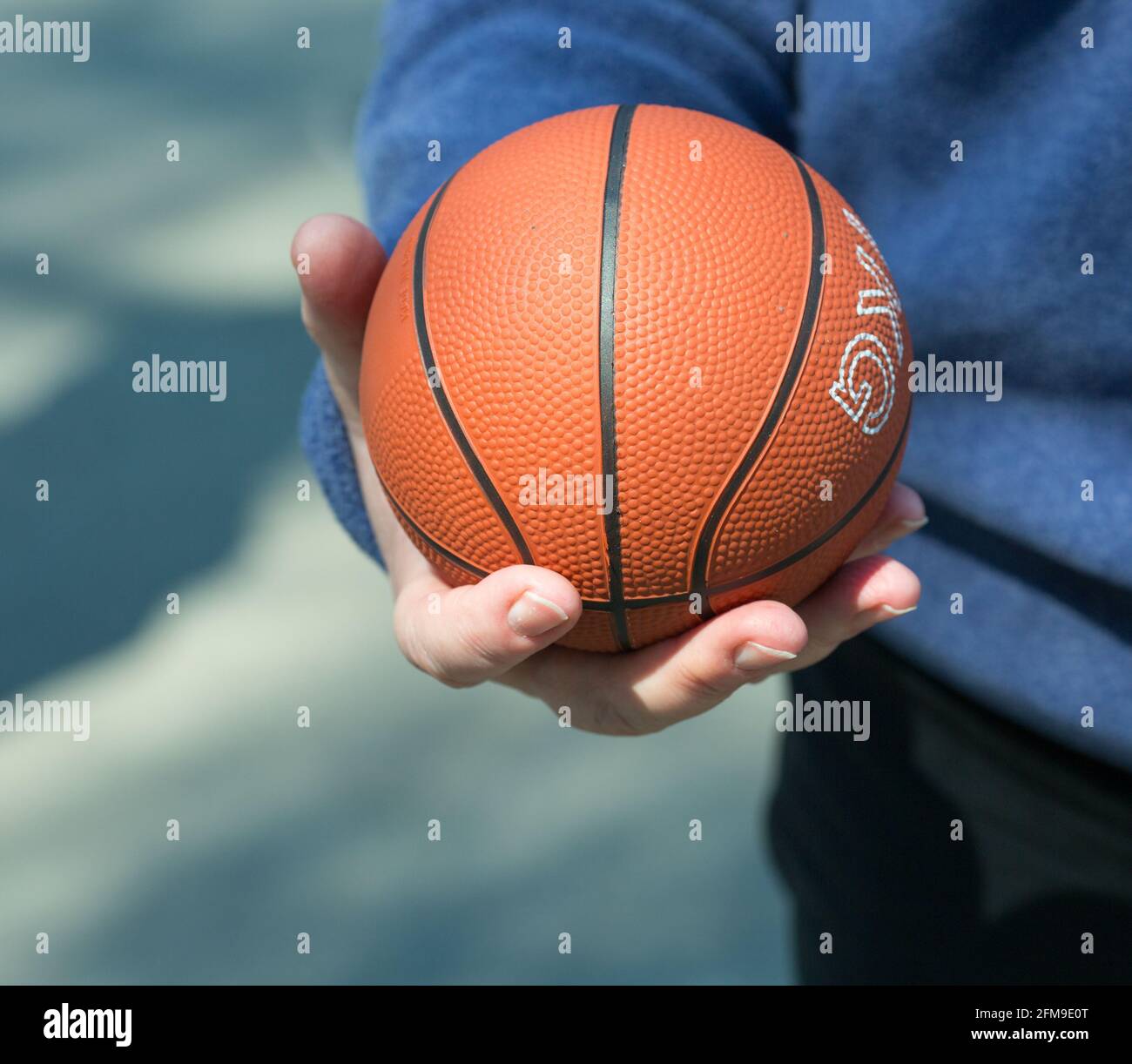 Die menschliche Hand hält den Ball. Der Ball ist orange. Der Mann fing gerade einen Mini-Basketball-Ball. Stockfoto