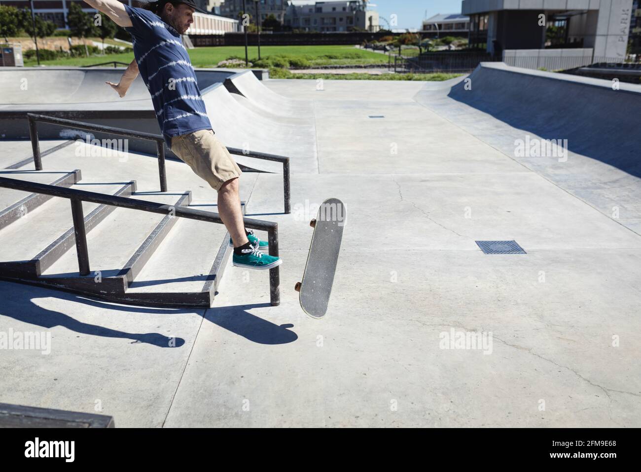 Kaukasischer Mann, der an einem sonnigen Tag vom Skateboard fällt Stockfoto