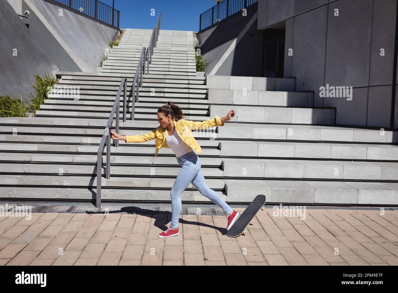 Kaukasische Frau fällt vom Skateboard neben Treppen Stockfoto