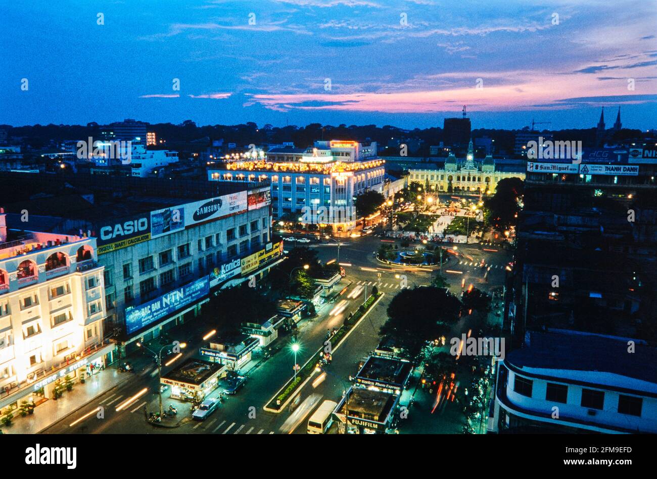 Nguyen Hue Street in Ho Chi Minh City bei Nacht mit dem Alten Rathaus am Ende der Straße und dem legendären Rex Hotel, auf der linken Seite am Verkehr Stockfoto