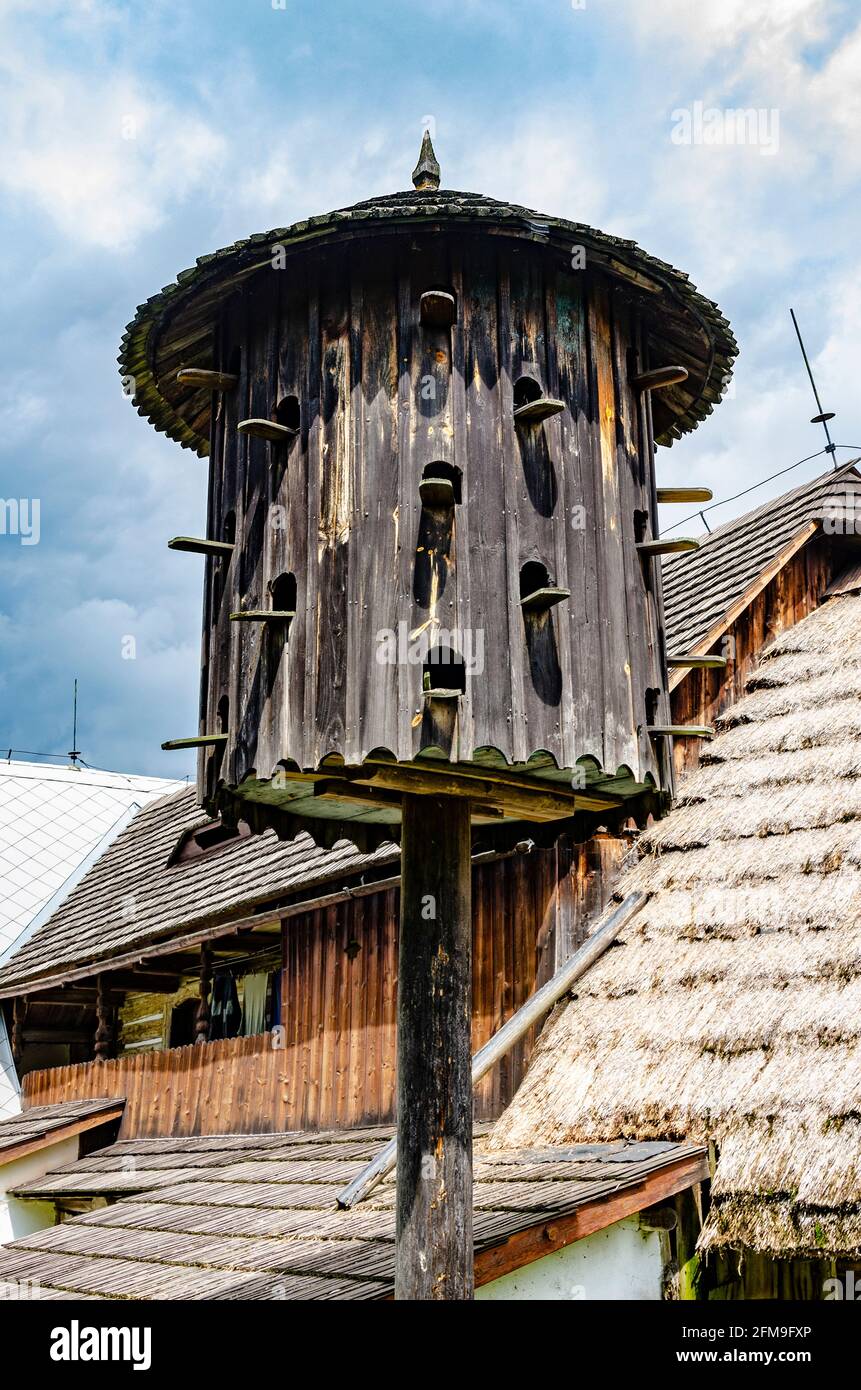 Vintage verwitterte hölzerne abgerundete Dovecote mit alten Häusern auf dem Hintergrund Im ländlichen Freilichtmuseum Stockfoto Vintage verwitterte hölzerne abgerundete Dovecote mit alten Häusern auf dem Hintergrund Im ländlichen Freilichtmuseum Stockfoto