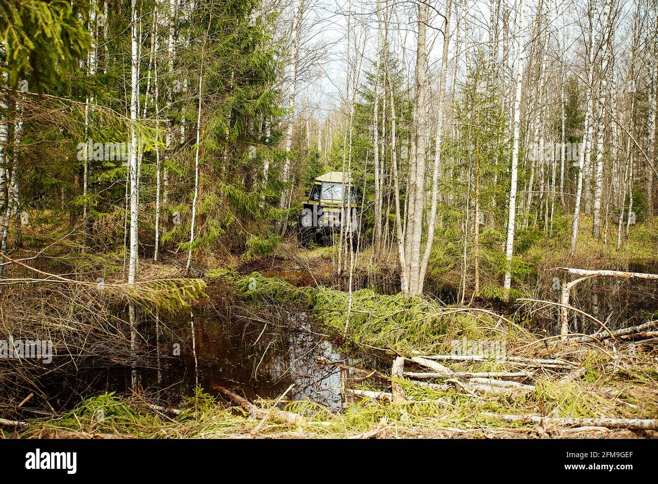 Ein Allradantrieb-Geländewagen fährt durch den Wald durch den Schlamm. Ein passierbarer SUV mit großen Rädern und hoher Durchfahrtshöhe. Spezieller Transpo Stockfoto