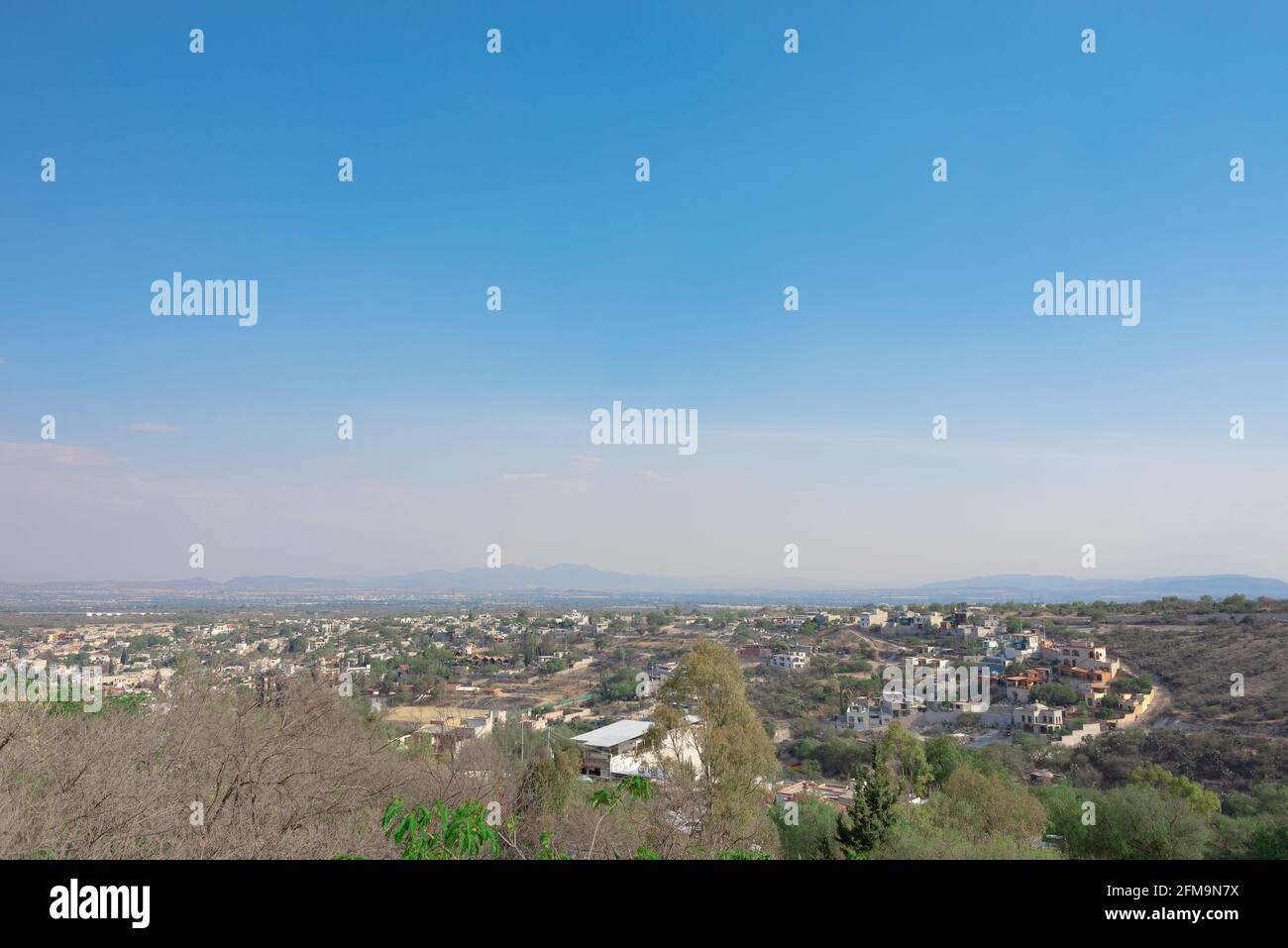 Blick auf ein armes Dorf von einem Berg aus, blauer wolkig Himmel in der Ferne, trockenes Wetter Stockfoto