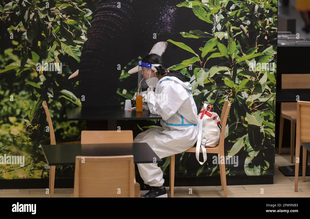 ELFENBEINKÜSTE, Abidjan, Flughafen, Corona-Wahnsinn, chinesische Frau mit Ganzkörperschutzkleidung während der Corona Pandemie, Saftkonsum im Flughafenrestaurant / ELFENBEINKÜSTE, Abidjan, Flughafen, Chinesische in Schutzkleidung während der Corona Pandemie Stockfoto