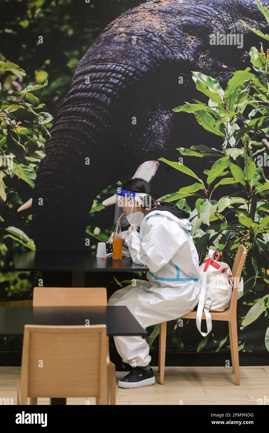 ELFENBEINKÜSTE, Abidjan, Flughafen, Corona-Wahnsinn, chinesische Frau mit Ganzkörperschutzkleidung während der Corona Pandemie, Saftkonsum im Flughafenrestaurant / ELFENBEINKÜSTE, Abidjan, Flughafen, Chinesische in Schutzkleidung während der Corona Pandemie Stockfoto