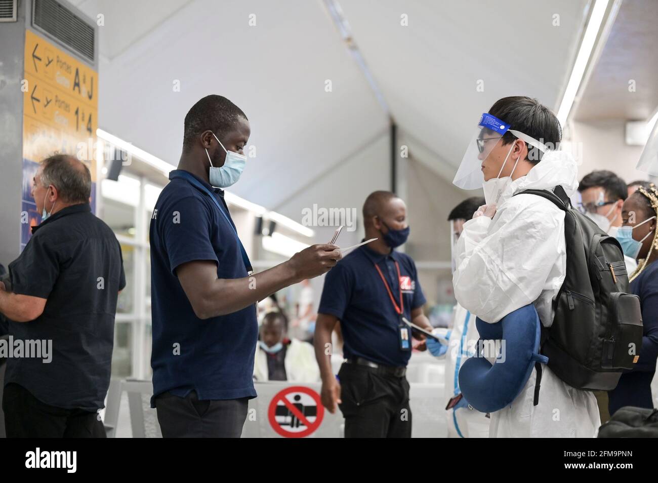 ELFENBEINKÜSTE, Abidjan, Flughafen, chinesischer Reisender mit Schutzkleidung während der Corona Pandemie-Zeit am Flugsteig nach Paris, Passkontrolle / ELFENBEINKÜSTE, Abidjan, Flughafen, Chinesische Reise in Schutzkleidung während der Corona Pandemie Stockfoto