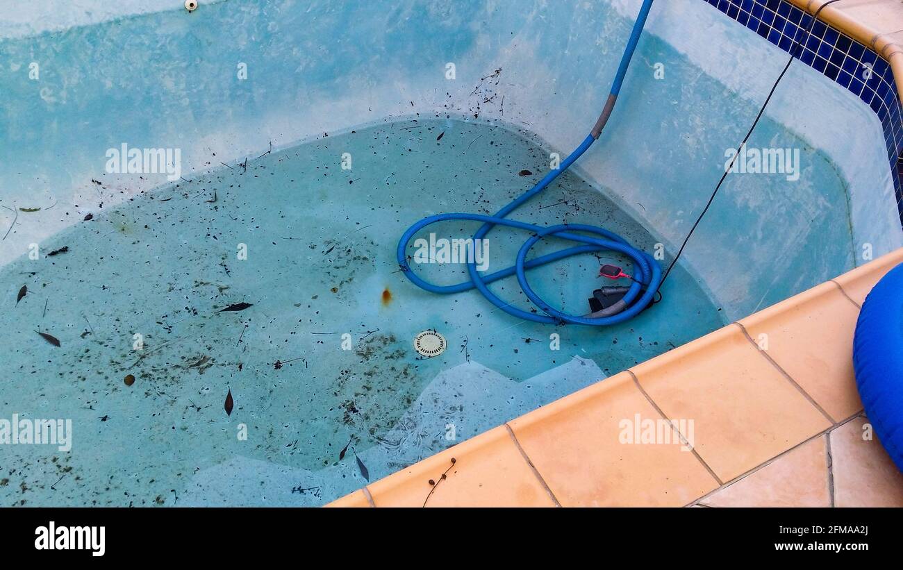 Elektrische Pumpe im Boden des verschmutzten, undichten Schwimmbades entfernen Wasser, damit der Pool repariert werden kann Stockfoto