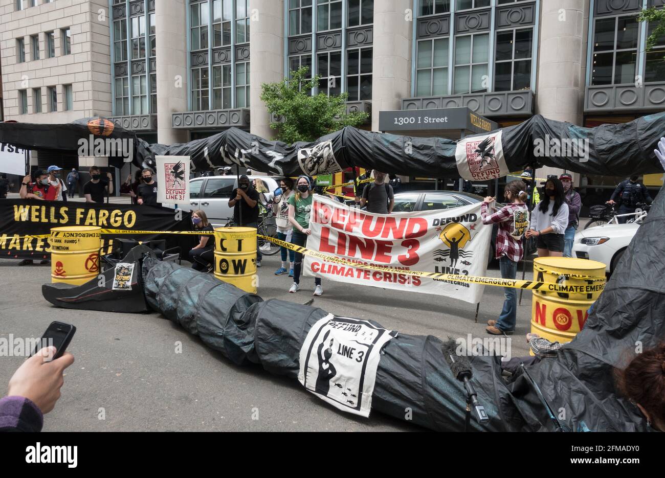 Demonstranten, die gegen den Bau der Pipeline-Erweiterung der Linie 3 protestieren, bringen ihre schwarze Pipeline „Schlange“ zu einer Wells Fargo-Bank, einer der Banken, die Baugelder an Enbridge, das kanadische Pipeline-Unternehmen, das die Ölpipeline mit Teersand baut, leihtt. Aktivisten sagen, dass die Pipeline ein großes Risiko für Ölausfälle und Umweltschäden darstellt und hoffen, Wells Fargo und andere Banken unter Druck zu setzen, sich von Endridge zu lösen. 7.Mai 2021. Washington, DC. Stockfoto