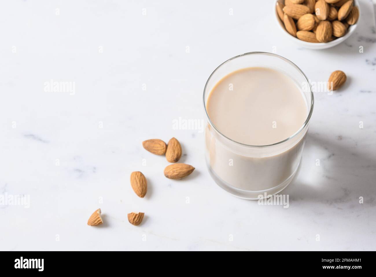 Mandelmilch im Glas auf weißem Hintergrund. Nahaufnahme. Gesunde vegane Ernährung. Mangel an Cholesterin. Laktosefrei. Stockfoto