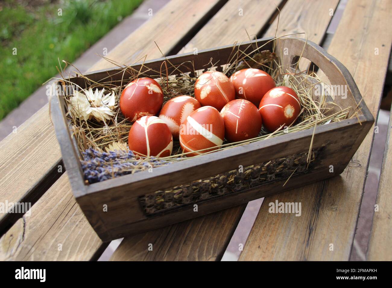 Ostereier gefärbt mit natürlichen Farben in einem Osterkorb mit Heu, außen, Tisch Stockfoto