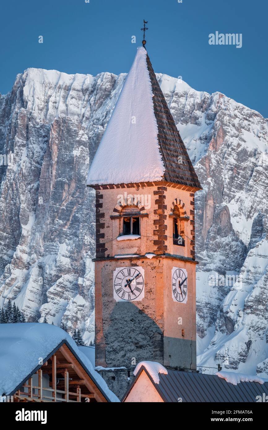 Der Uhrenturm der Kirche von Sappade im Winter, im Hintergrund der Berg Civetta, Dolomiten. Gemeinde Falcade, Belluno, Venetien, Italien Stockfoto