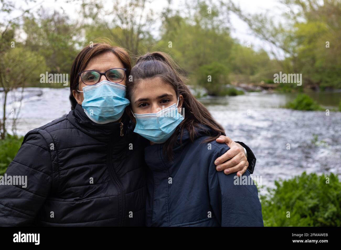 Selektiver Fokus einer Mutter und Tochter mit Masken für Das Coronavirus porträtiert sich selbst mit einem Strom Des Wasserkonzepts Natur Gesundheit Stockfoto