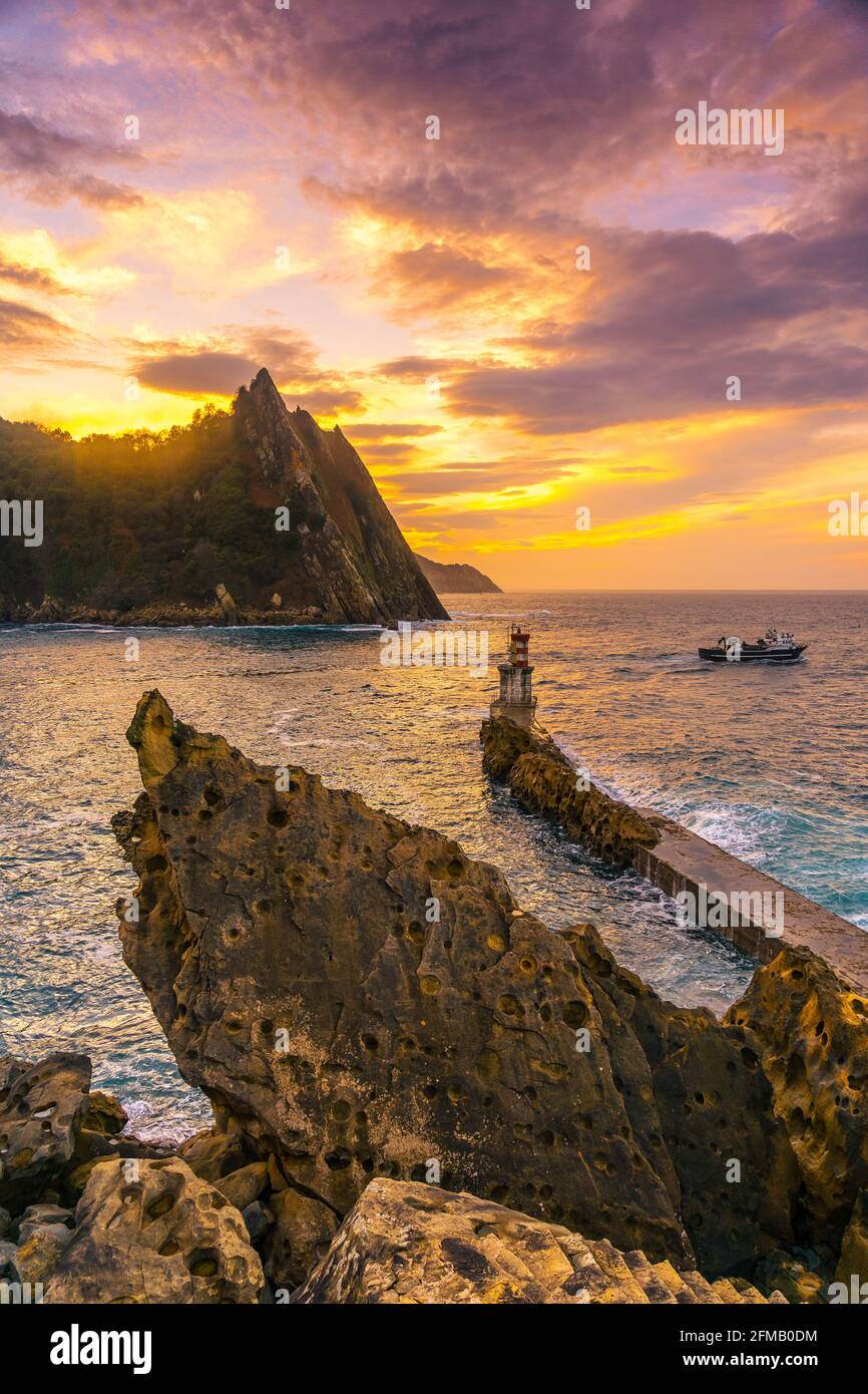 Boot verlässt den Leuchtturm in der Gemeinde Pasajes San Juan, Gipuzkoa, Spanien bei Sonnenuntergang Stockfoto