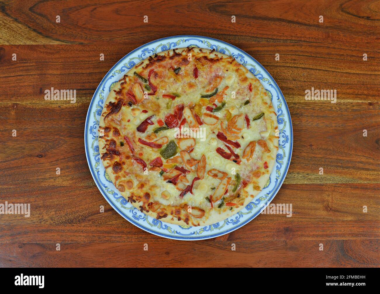 Platte mit Hühnerpizza mit Paprika auf einem Holztisch Stockfoto
