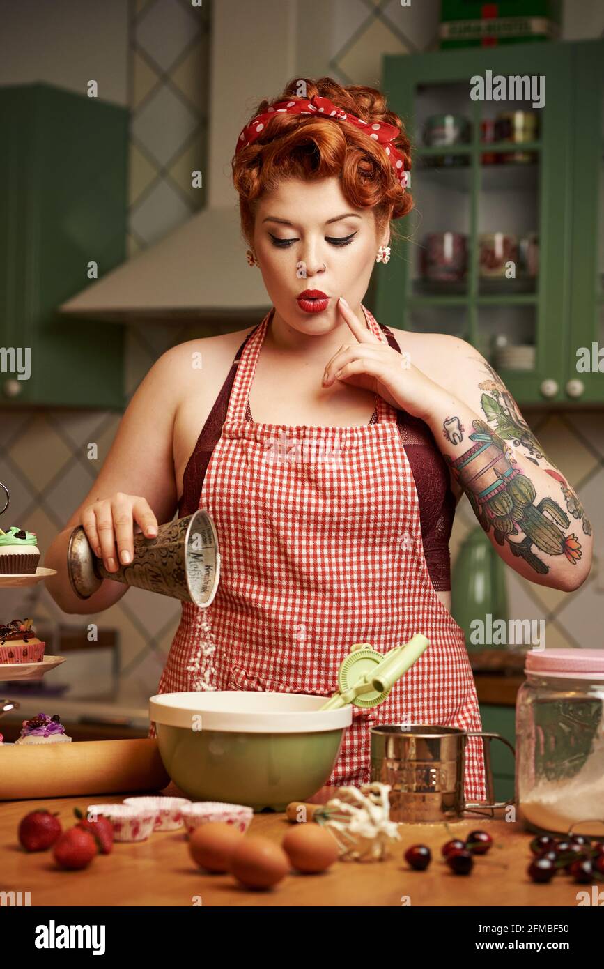 Pin-up Mädchen mit roten Haaren Backen in der Küche Stockfoto