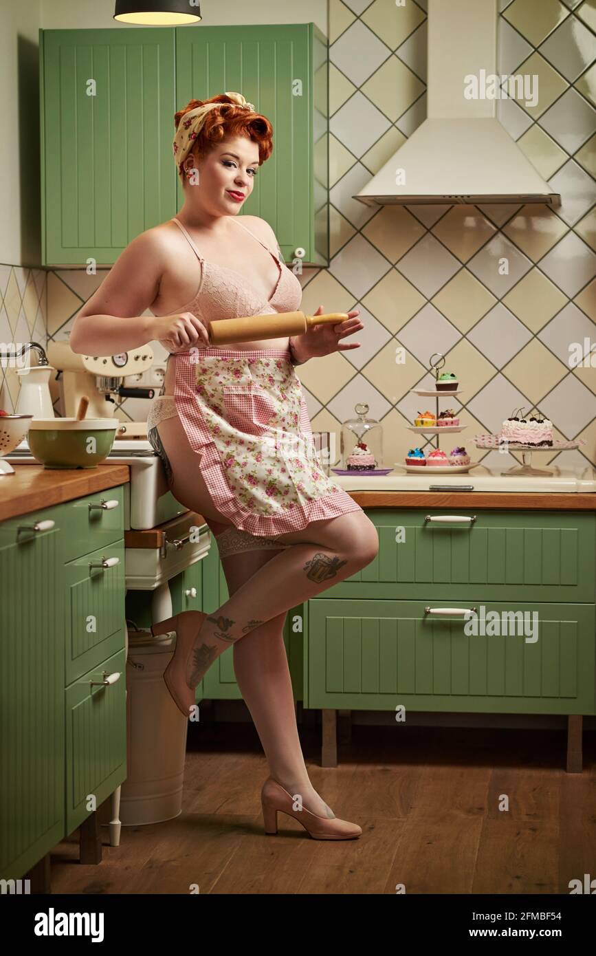 Pin-up Mädchen mit roten Haaren Backen in der Küche Stockfoto