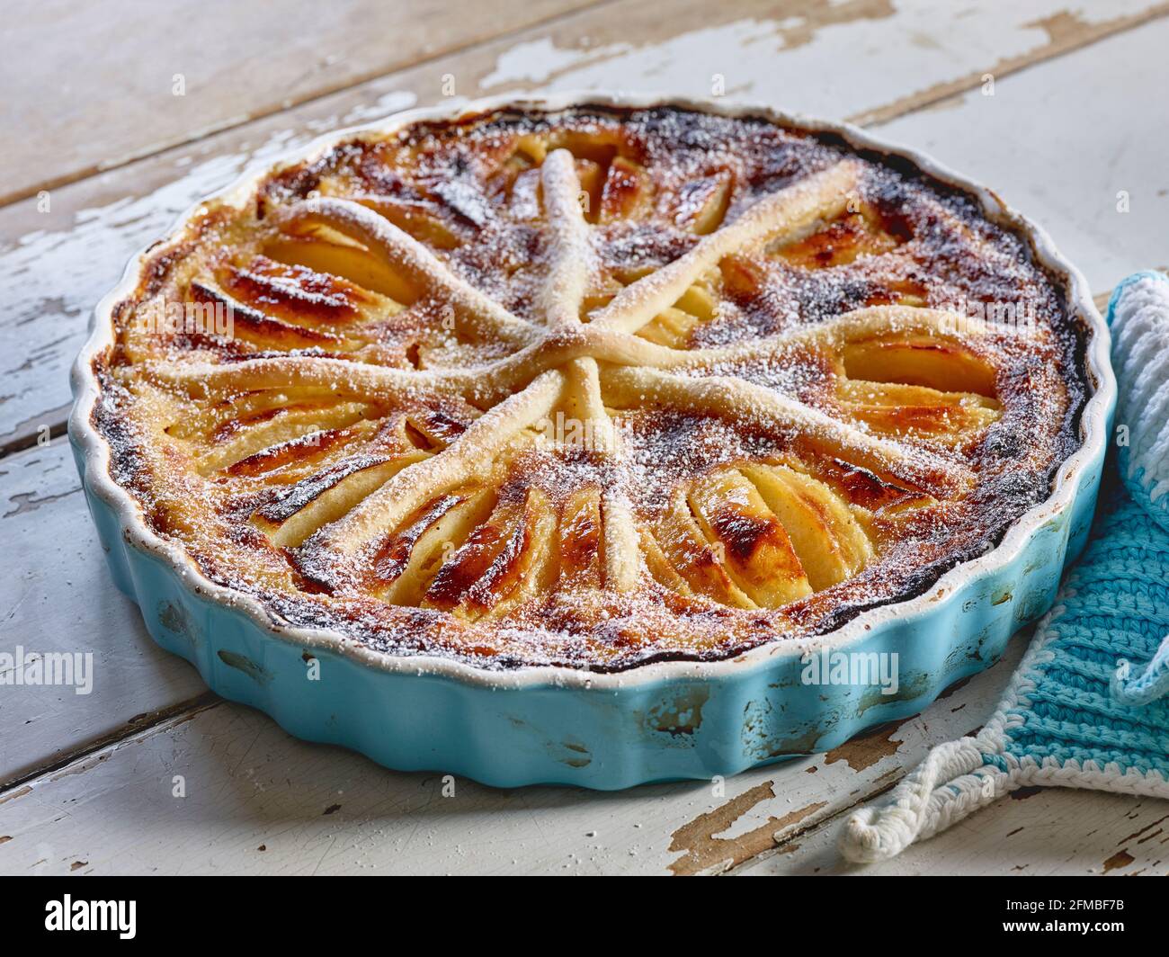 Ein gebackener „Elsässer-Art“-Apfelkuchen in hellblauer Torte Form mit ...