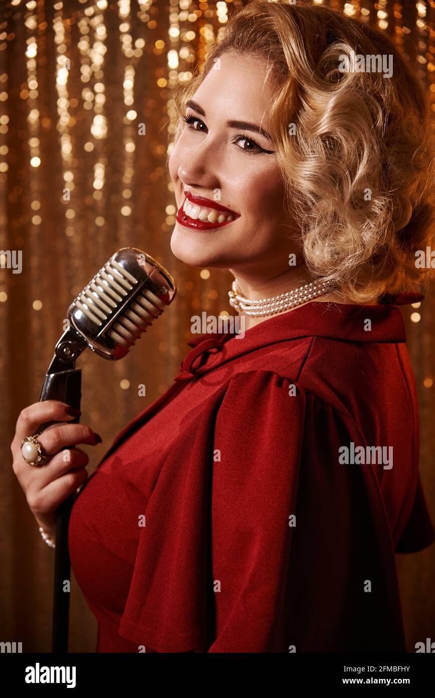 Junge Frau mit blondem Haar im Marilyn Monroe-Stil mit Mikrofon Stockfoto