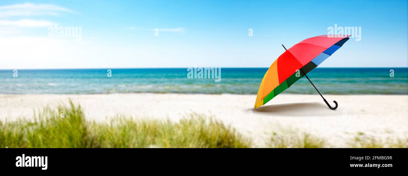 Farbenfroher Sonnenschirm am Strand am Meer Stockfoto