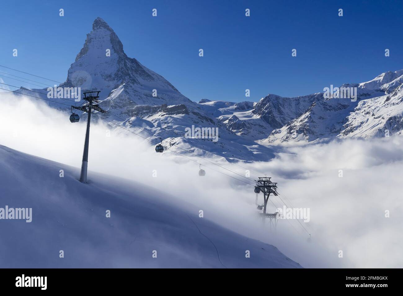Während das Mattertal in dichten Nebel gehüllt ist, scheint die Sonne wunderschön darüber und zieht Wintersport an. Mit der Gornergratbahn oder der Seilbahn kommt man von Zermatt aus in wenigen Minuten über die Nebellinie. Stockfoto