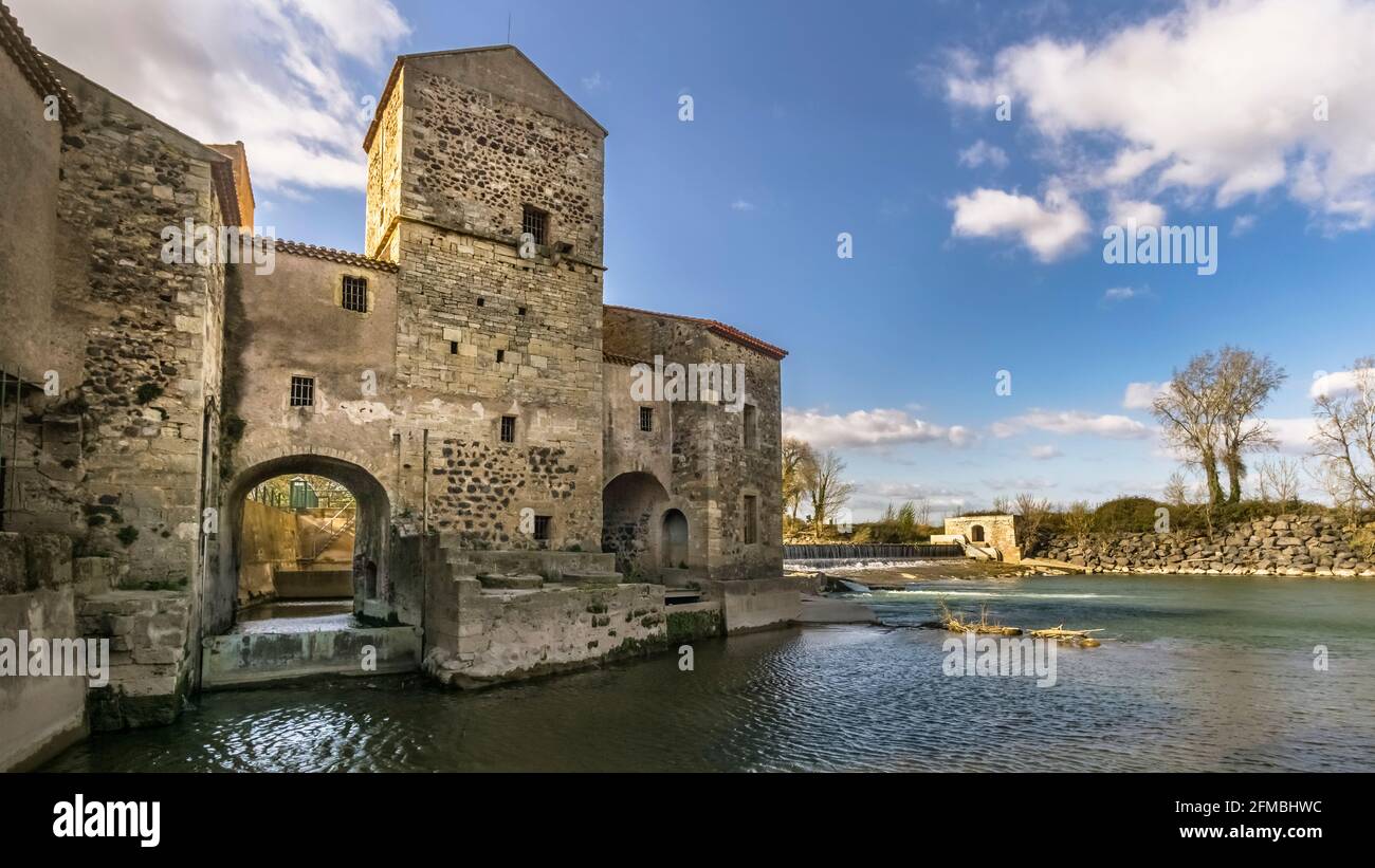 Alte benediktinische Mühle am Fluss Hérault in der Nähe von Saint Thibéry. Es wurde im 13. Jahrhundert erbaut. Im Jahr 1998 wurde es in ein kleines Wasserkraftwerk umgewandelt. Stockfoto