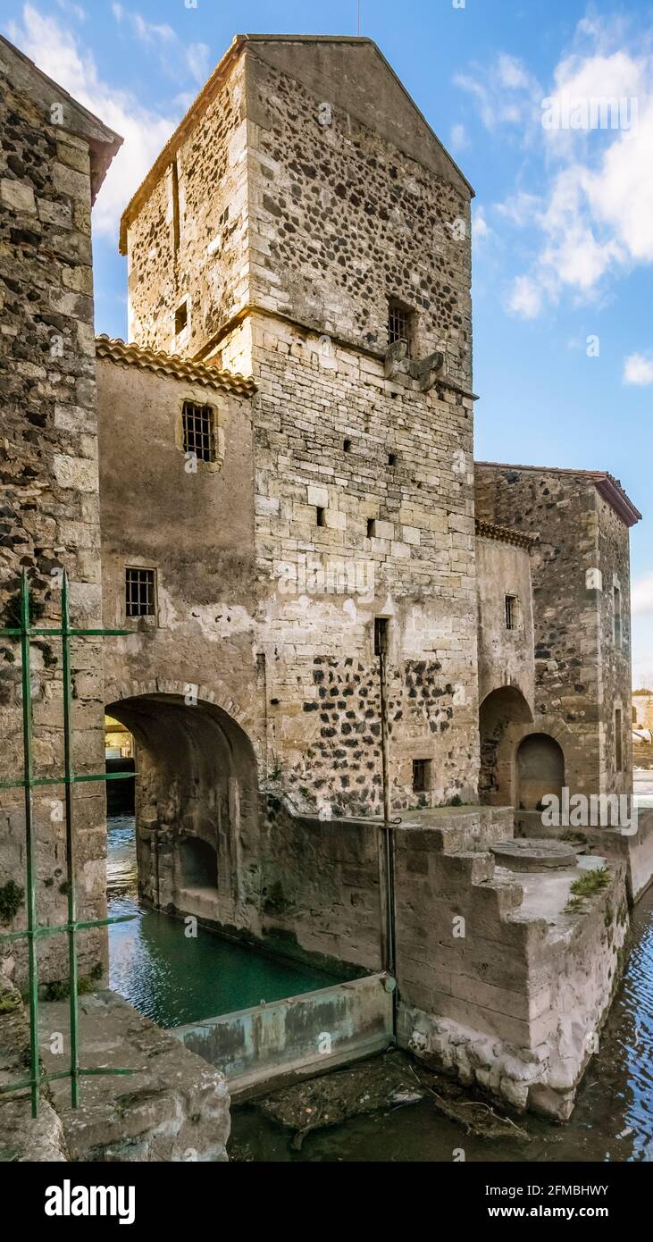 Alte benediktinische Mühle am Fluss Hérault in der Nähe von Saint Thibéry. Es wurde im 13. Jahrhundert erbaut. Im Jahr 1998 wurde es in ein kleines Wasserkraftwerk umgewandelt. Stockfoto