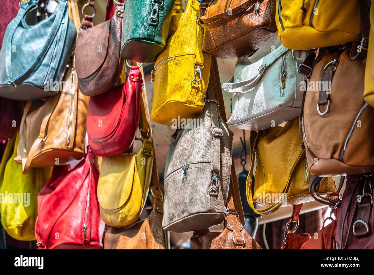 Viele Ledertaschen bunte lebendige Farben hängen auf dem Display in Einkaufsstraßen Markt in Florenz, Florenz, Toskana, Italien Stockfoto