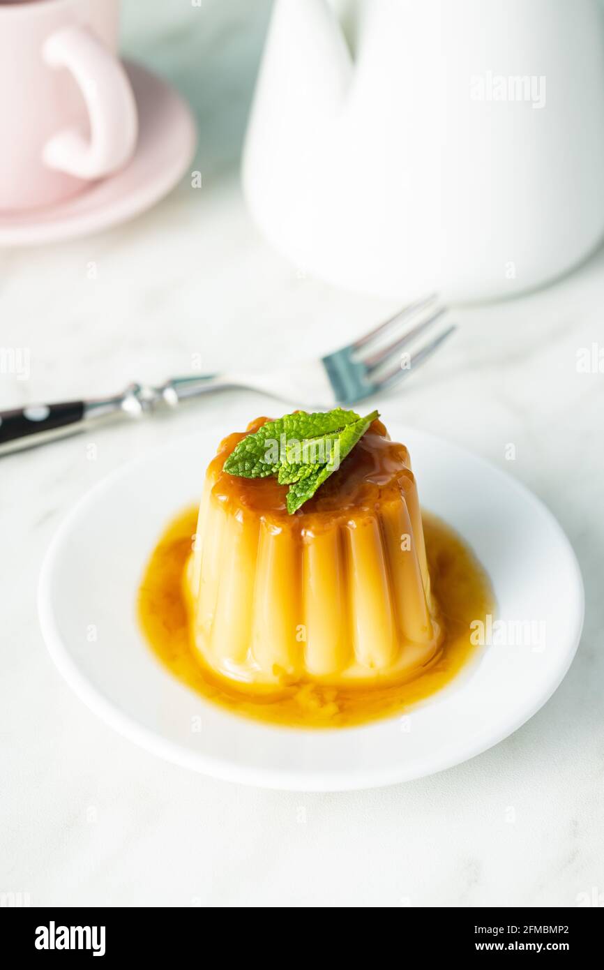 Süßer Vanillepudding. Süßes Dessert mit Karamell-Belag auf weißem Tisch. Stockfoto