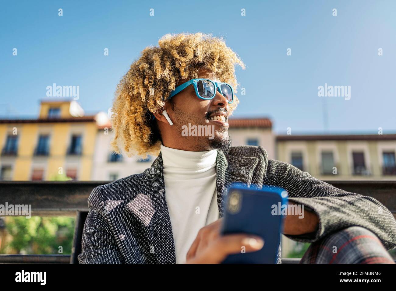 Hübscher, intelligenter afrikanischer Mann, der auf der Straße mit dem Mobiltelefon Musik hört. Kommunikationskonzept Stockfoto