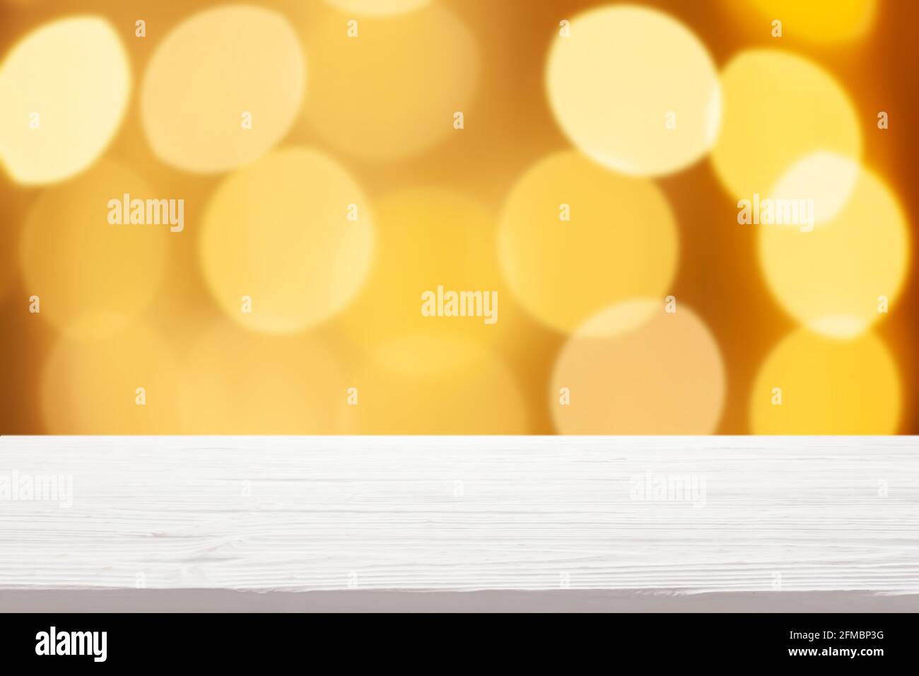 Weiße Holztischplatte auf unscharfen gelben weihnachtsbaumleuchten Hintergrund Stockfoto
