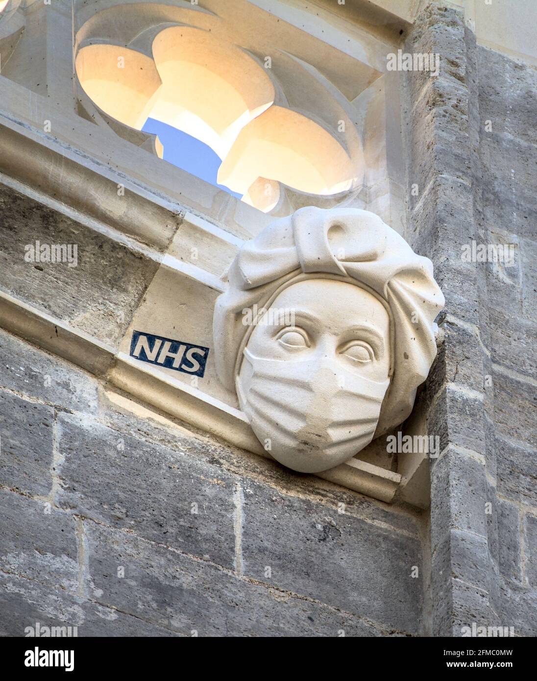 Geschnitzte Steinskulptur auf Christchurch Priorat EINES National Health Service, NHS, Krankenschwester trägt EINE PSA Maske in Bezug auf die Covid-19 Coronavirus Pande Stockfoto