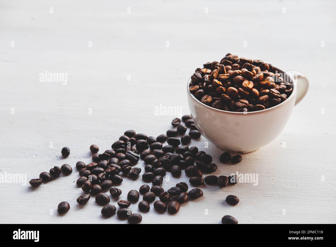 Geröstete Kaffeebohnen in einer Kaffeetasse auf einem weißen Tabelle Stockfoto