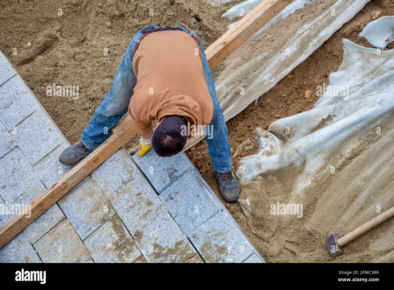 Arbeiter, der das Flussufer mit Granitstein stärkt. Stockfoto