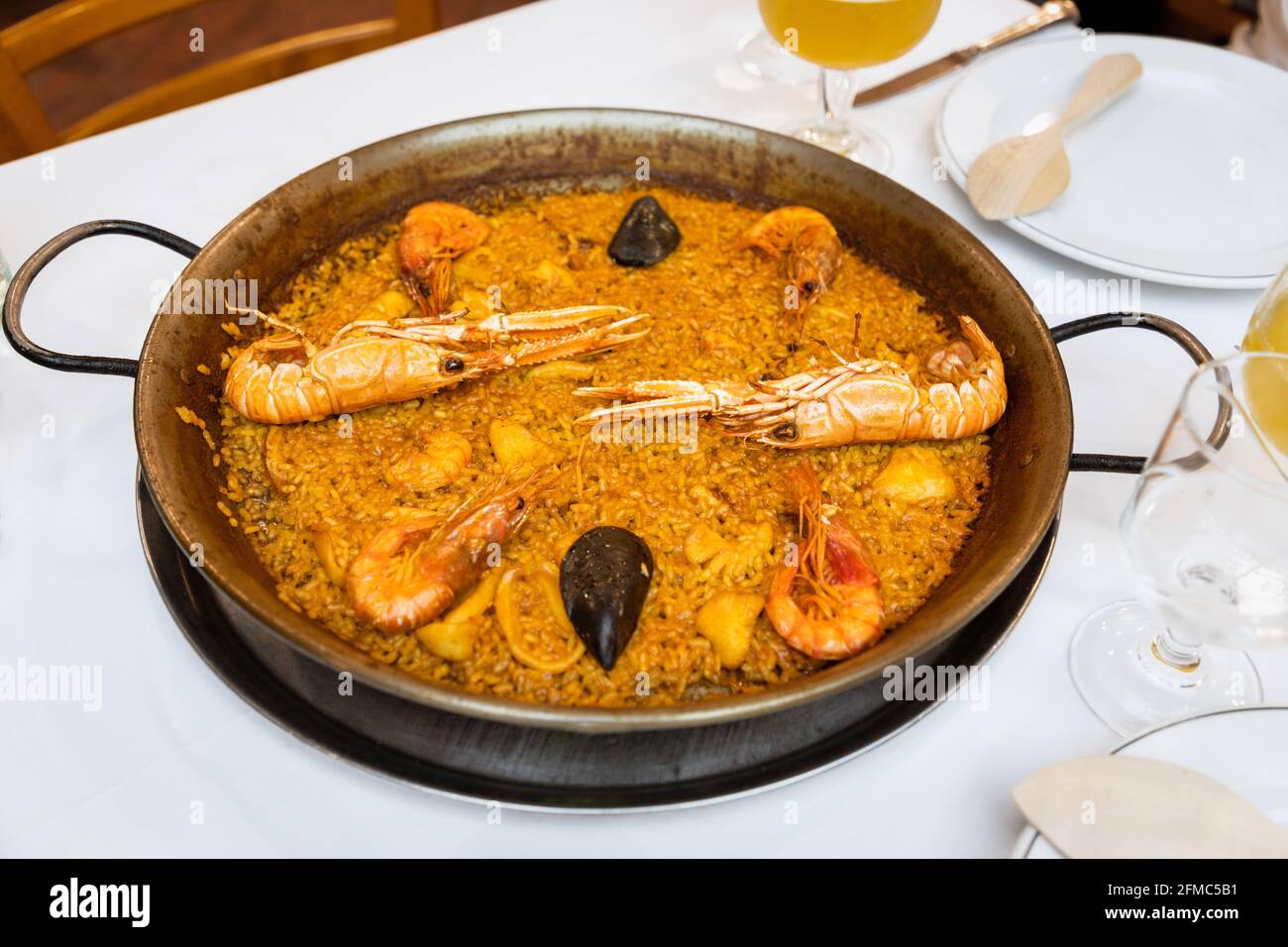 Köstliche Paella mit traditionellen valencianischen Meeresfrüchten (herzhaftes Reisgericht mit Garnelen, Tintenfisch und Muscheln) in der Paella-Pfanne Stockfoto