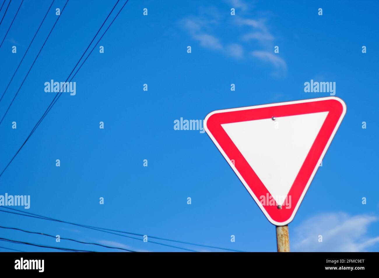 Unschärfe-Effekt leere Dreieck rot Warnschild mit blauem Himmel Hintergrund. Gefahrenrichtung. Nicht fokussiert. Stockfoto