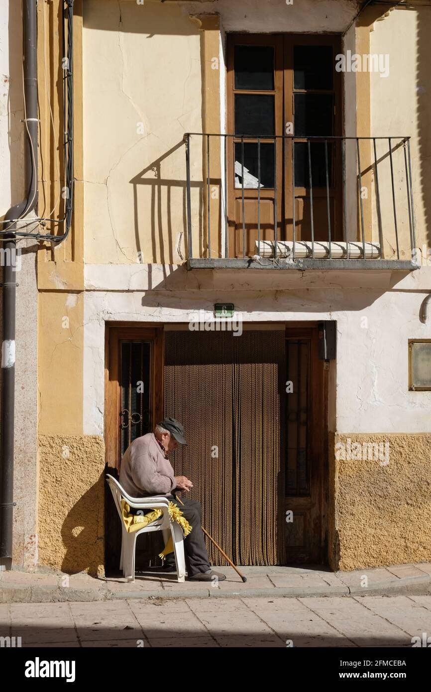Ein alter Mann mit einer Truckerkappe sitzt in der Sonne vor seinem Haus in Libros, in der Nähe von Teruel, Aragon, Spanien Stockfoto