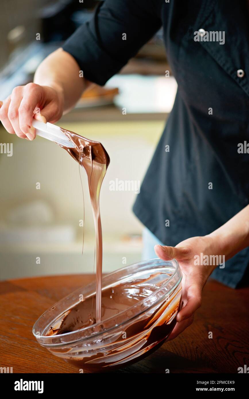 Der Konditor temperiert heiße dunkle Schokolade. Desserts werden zubereitet. Weicher, selektiver Fokus. Stockfoto