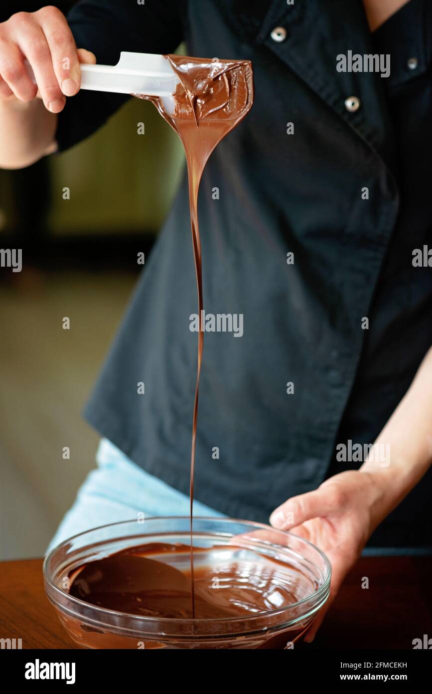 Der Konditor temperiert heiße dunkle Schokolade. Desserts werden zubereitet. Weicher, selektiver Fokus. Stockfoto