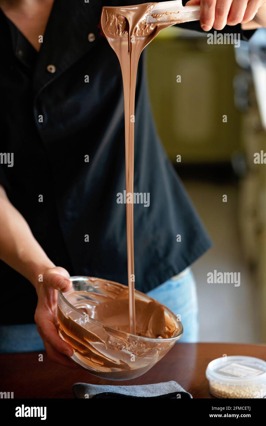 Der Konditor temperierte heiße Milchschokolade. Desserts werden zubereitet. Weicher, selektiver Fokus. Stockfoto