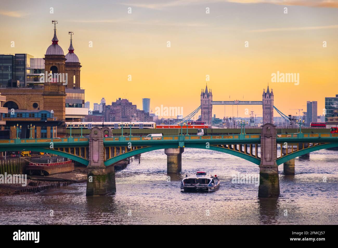 Orangefarbener Sonnenuntergang mit dem Stadtbild Londons, einschließlich Cannon Street Railway Bridge, Southwark Bridge und Tower Bridge Stockfoto